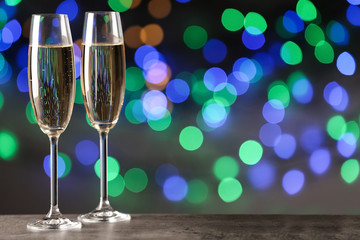 Glasses of champagne on table against blurred lights, space for text. Bokeh effect