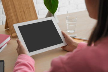 Woman using tablet at table, closeup. Space for design