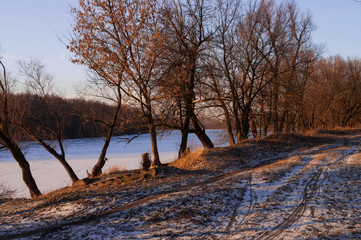 Frost river with snowand naked trees. Winter sunset in warm brown colors 