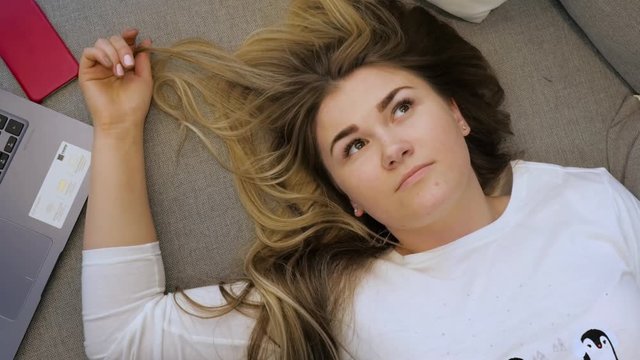 Young girl lying on the sofa and thinking looking at the ceiling