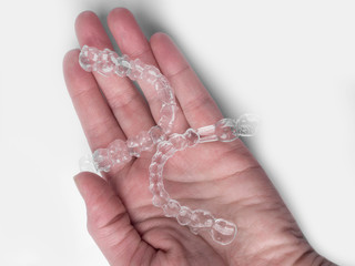 Taking care of teeth. Close up of clear aligners in hands, orthodontic device. Selective focus and...