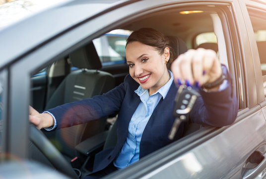 Young businesswoman sitting in car holding car keys