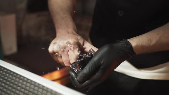 Bartender carves piece of ice using ice pick close up 