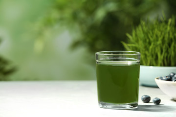 Glass of spirulina drink on table against blurred background, space for text