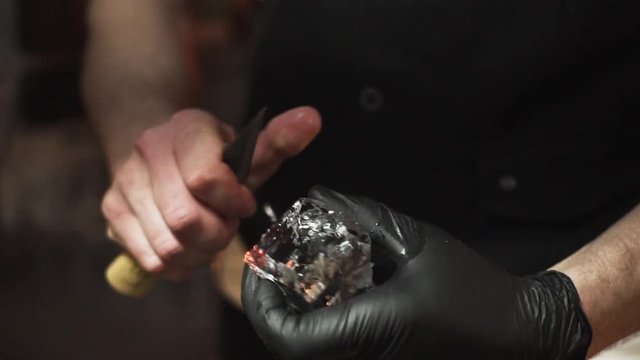 Bartender carves piece of ice using ice pick close up 