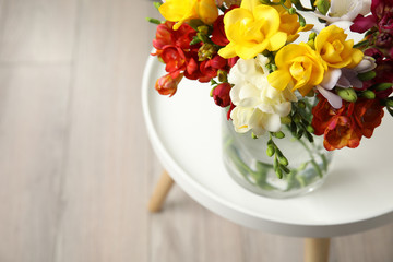 Beautiful spring freesia flowers in vase on table, view from above. Space for text