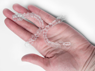 Ready to adjust my teeth. Hand is holding transparent orthodontic device for improving bite.