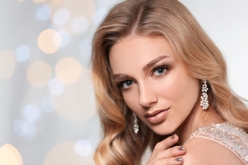 Beautiful young woman with elegant jewelry against defocused lights. Space for text