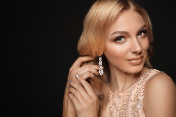 Obraz premium Beautiful young woman with elegant jewelry on dark background. Space for text
