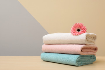 Stack of fresh towels with flower on table. Space for text