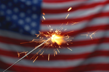 Burning sparkler against USA flag, closeup. Happy Independence Day