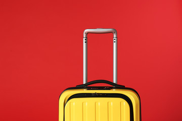 Stylish yellow suitcase with handle on color background