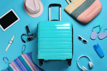 Flat lay composition with suitcase and accessories on color background, space for text. Summer...