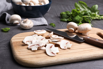 Wooden board with sliced raw mushrooms on table