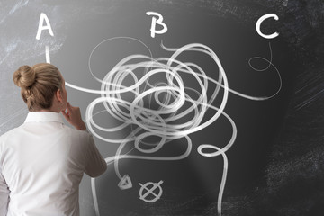 decision making concept with rear view of woman looking at chalkboard with arrows pointing in...