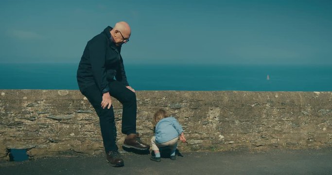Little toddler on the coast with his grandfather