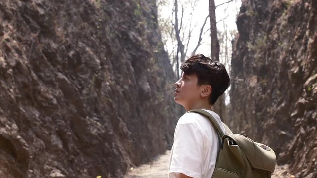 tourist asian guy looking at falling leaves in a rock moutain while trekking in the forrest