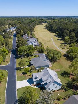 High angle aerial view of houses with golf course in background.