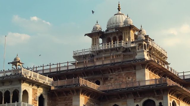 Panning shot of Albert Hall Ram niwas bagh with birds flying and cloudy skies, shows a tourist landmark in Jaipur rajasthan