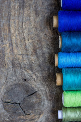 Flat lay composition with colorful sewing threads on wooden background. Fashion concept. Copy space.