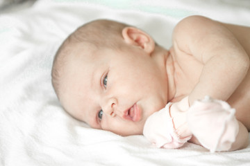 Closeup portrait of cute newborn baby lying down in the bed at home, smiling face, happy childhood, new life concept