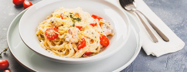 Delicious salmon linguine pasta dish with herbs and grilled salmon filet.