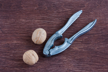 old metal nutcracker and two walnuts on wooden table