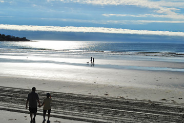 Fototapeta na wymiar People Walking on a Cloudy Day at the Beach