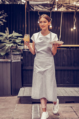 Delighted young woman brining food to the guests