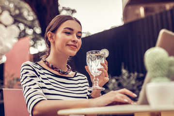 Delighted positive woman holding a delicious cocktail