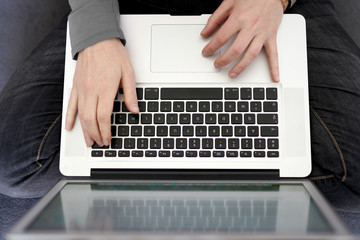 A person manipulating on his gray laptop