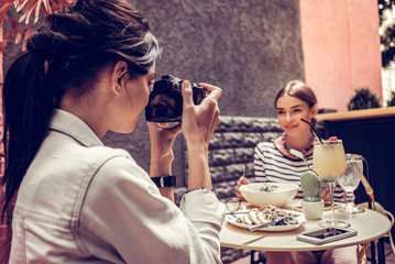 Delighted nice woman taking a photo of her friend