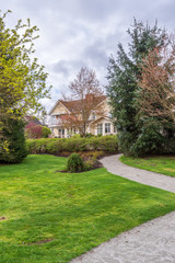 Beautiful exterior of newly built luxury home. Yard with green grass and walkway lead to front entrance.