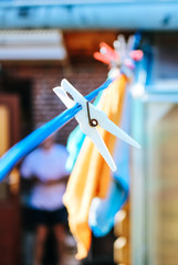 Close up of a white clothespin (peg, clip) on an outdoor laundry line with wash cloths hanging in the background.