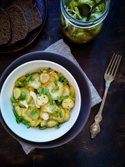 Salad of pickled cucumbers with onions in a bowl, on a light background top view. Next to a fork, rye bread and jar with salad.