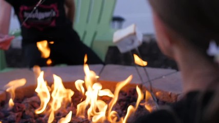 HEBER, UNITED STATES - 02/14/2019: 2 Girl Kids Are Roasting Marshmallow On Open Flame With The Sticks. Hand held shot from behind shoulder of a girl as she and he friend are tasting white marshmallow 