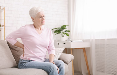 Senior woman suffering from backache at home