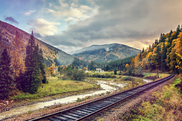 Fototapeta premium Dramatic Picturesque Scene. railway in the autumn Mountain landscape. Overcast Clouds over the mountains. Concept of Travel. Retro Style .