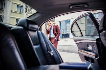 Businessman in purple suit talking on cellphone outside