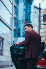 Handsome businessman entering and exiting his limo while looking sharp and serious.