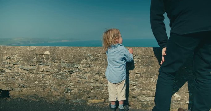 Little toddler and his grandfather looking at the sea
