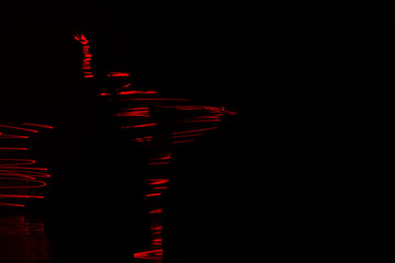 Ballet dancer dancing in front of and red light while expressing the hell with her magnificent dance moves. long exposure motion blur