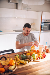 Young and healthy man putting fruits in his blender early in the morning.
