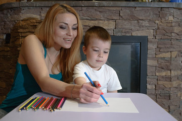 Happy mom and son draw and rejoice at home