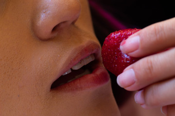 Close up Young woman with pink hair, ready to bite a delicious red strawberry erotically
