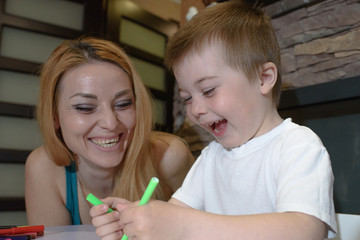 Happy mom and son draw and rejoice at home