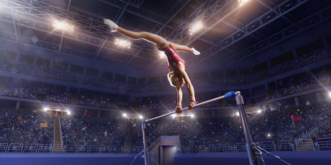 Female athlete doing a complicated exciting trick on horizontal gymnastics bars in a professional gym. Girl perform stunt in bright sports clothes