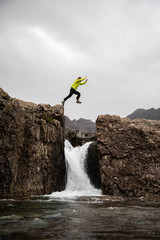 Hiker jumping over waterfall