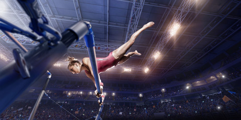 Female athlete doing a complicated exciting trick on horizontal gymnastics bars in a professional...