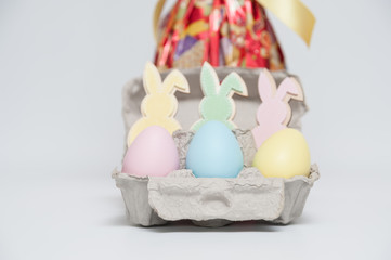 Colorful little easter eggs with ornament bunnies. Isolated on white background. Close-up. Easter egg in red packaging on the background defocused.